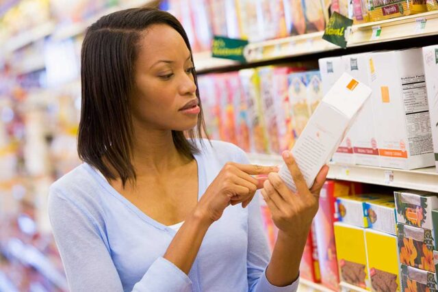Young woman in supermarket checking ingredients on a packet